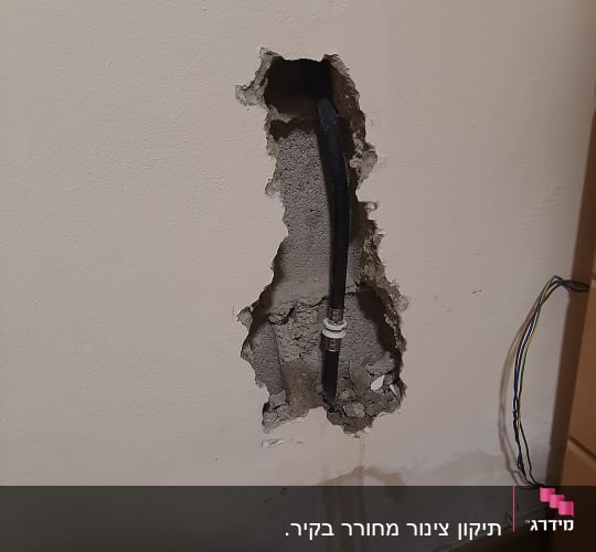 צינור שחור בקיר שבור עם חיבור מתכת